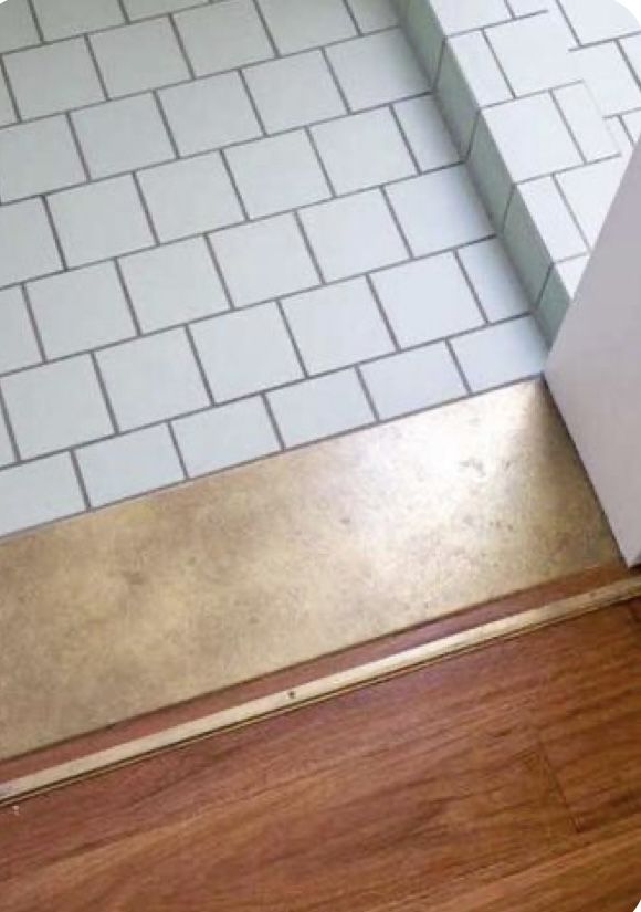 a bathroom with white tile and wood flooring next to a shower door that has the word forte written on it