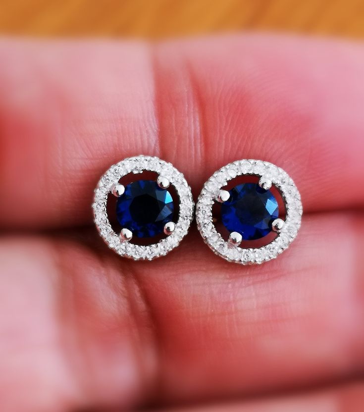 These Halo Blue Sapphire Stud Earrings are one of a kind. They look fabulous and beautiful when worn. This pair of Round Diamond Cut Blue Sapphire with Halo of Round shape simulated diamonds is excellent cut, Bright White D Color, and VVS1 Purity. These Earrings feature push backs for secure locking. Comes with a perfect Gift Box, Ideal for Gifting. A great gift for all occasions for your loved ones. Ultra-luxurious and sophisticated this dramatic diamonds Stimulant Halo earrings studs are made Sapphire Halo Design Drop Earrings, Blue Cubic Zirconia Halo Earrings, Blue Halo Design Earrings For Anniversary, Blue Diamond Round Earrings For Anniversary, Blue Round Cluster Earrings For Formal Occasions, Blue Halo Cubic Zirconia Earrings, Sterling Silver Halo Round Earrings, Round Cluster Earrings With Halo Setting, Round Sterling Silver Halo Earrings