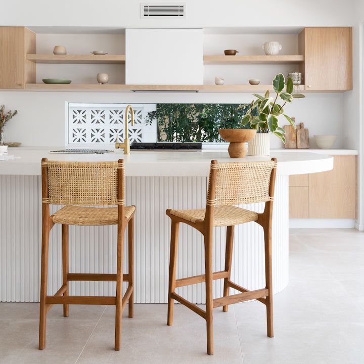 two wicker chairs sitting in front of a kitchen island with built - in shelving