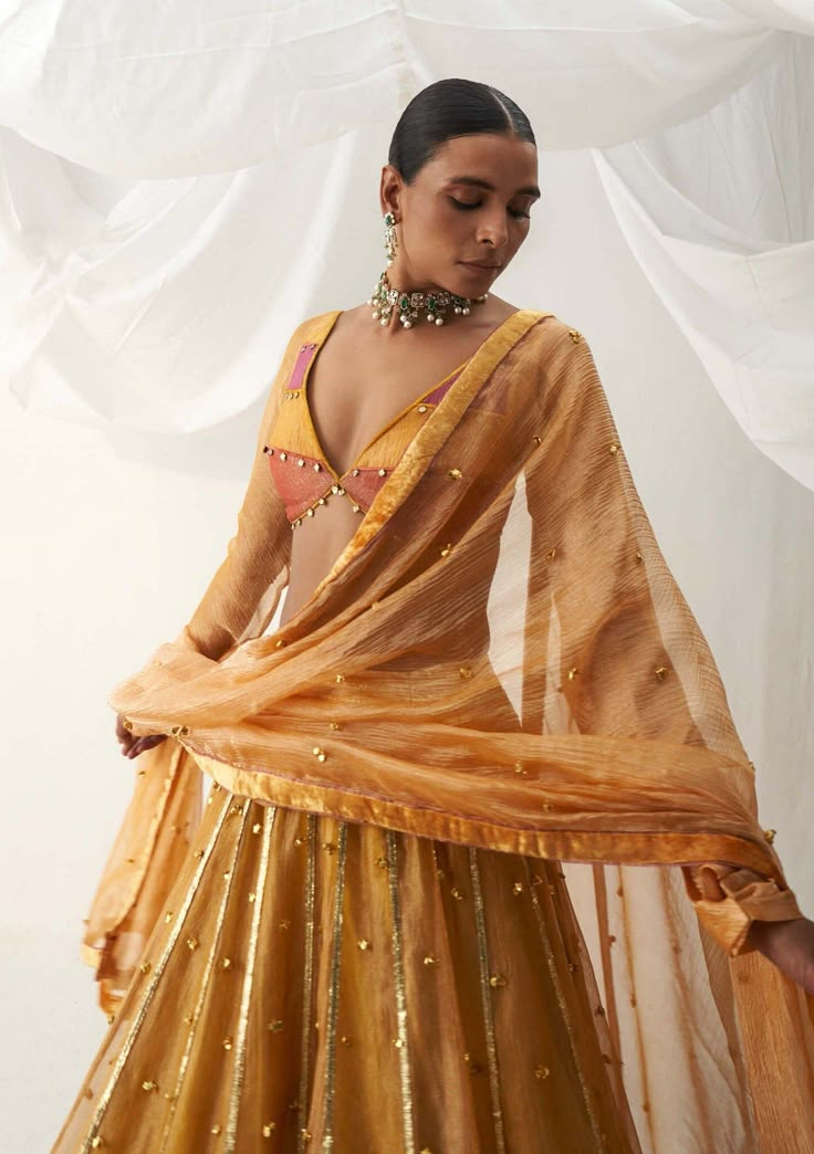 Editor's Note Elevate your style with our color-blocked choli-patterned blouse, featuring churi sleeves and a backless design, perfectly paired with a warm shade of mustard lehenga adorned with ghungroo sprinkling all over and gota stripes along the hem. This ensemble is completed with a tissue dupatta, making it an ideal choice for special occasions where you want to make a striking and fashionable statement with a touch of elegance and grace. Fabric: Lampi and tissue Color: Yellow Component: L Churi Sleeves, Mustard Lehenga, Choli Pattern, Tissue Dupatta, Indian Dress Up, Ghaghra Choli, Indian Outfits Lehenga, Yellow Lehenga, Traditional Indian Dress