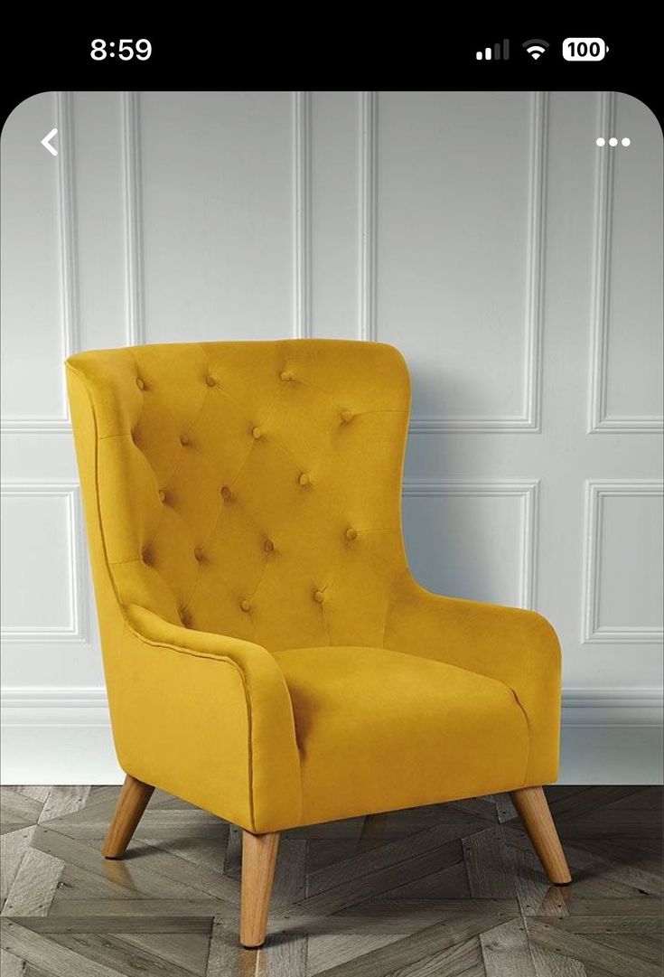 a yellow chair sitting on top of a wooden floor in front of a white wall