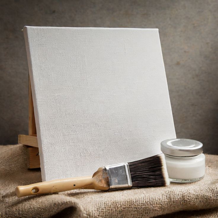 an easel with a paintbrush next to it on a piece of cloth and a jar of cream