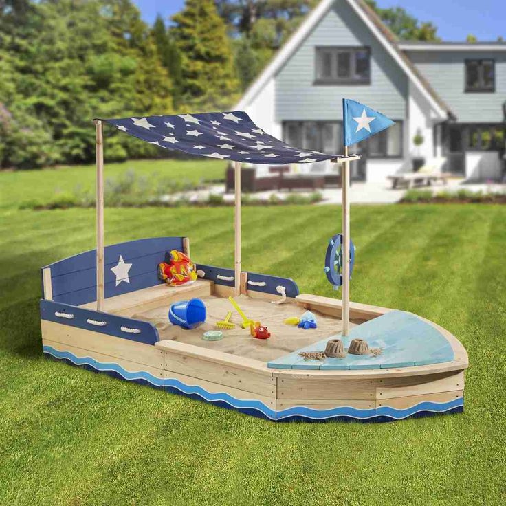 a wooden toy boat with an american flag on it in the grass next to a house