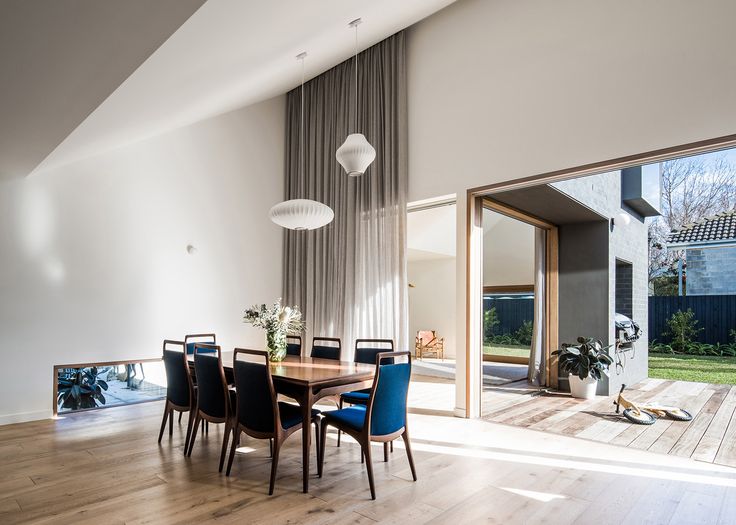 a dining room table with blue chairs in front of a sliding glass door that leads to the backyard