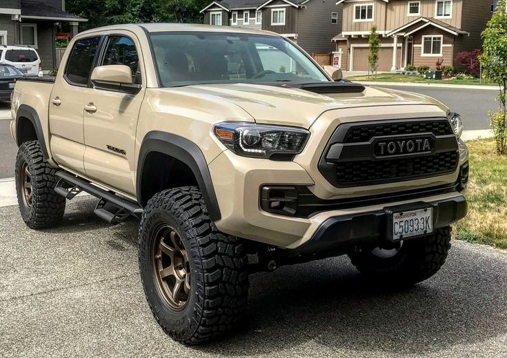 a tan toyota pickup truck parked in front of some houses