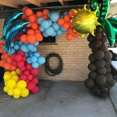 an arch made out of balloons in the shape of dolphins and palm trees is shown