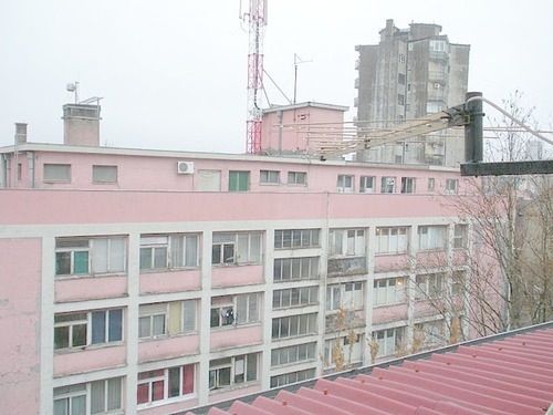 a pink building with lots of windows in front of it and a crane on the roof