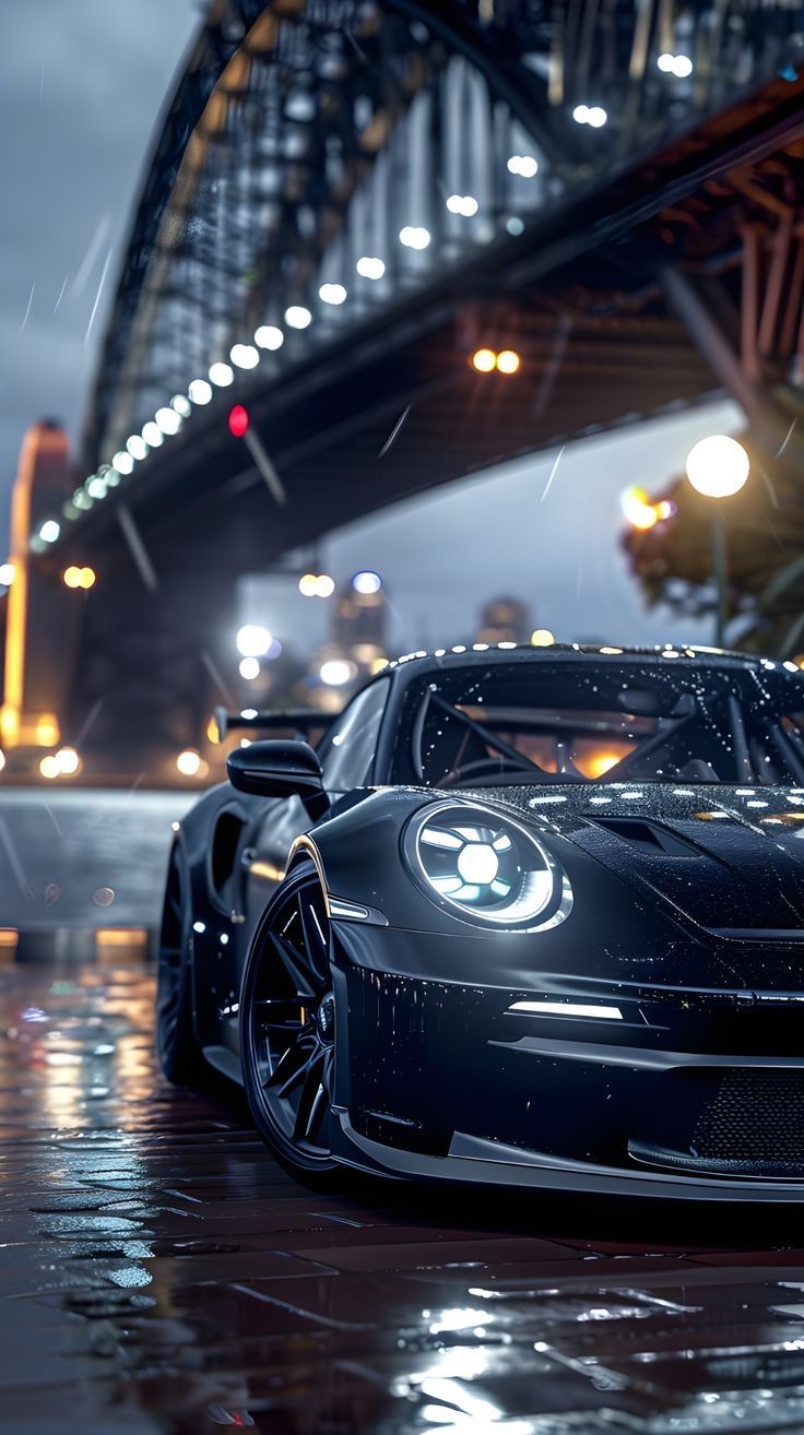 a black sports car parked in front of a bridge at night with the lights on