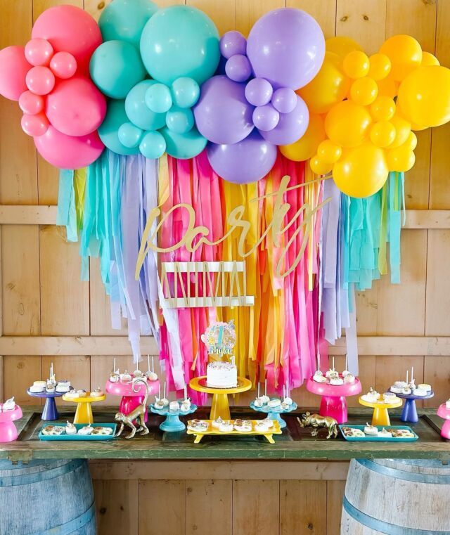 a table topped with lots of balloons and cake