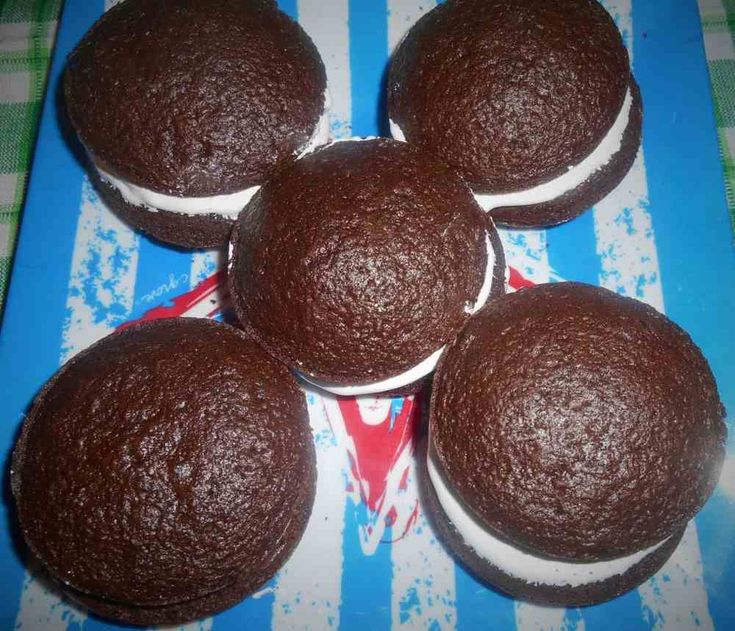 four chocolate cupcakes sitting on top of a blue and white tablecloth with red stripes