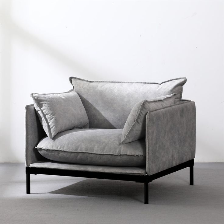 a gray couch with two pillows on it and a white wall in the back ground