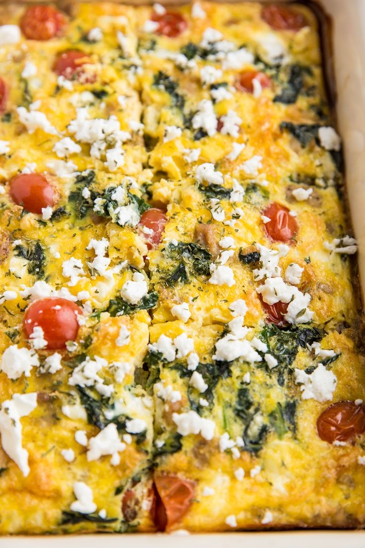 a casserole dish with tomatoes, cheese and spinach