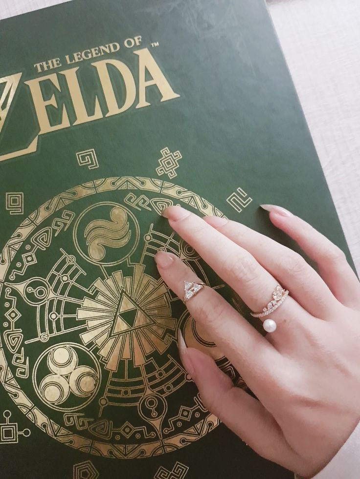 the legend of zelda book is being held by a woman's hand