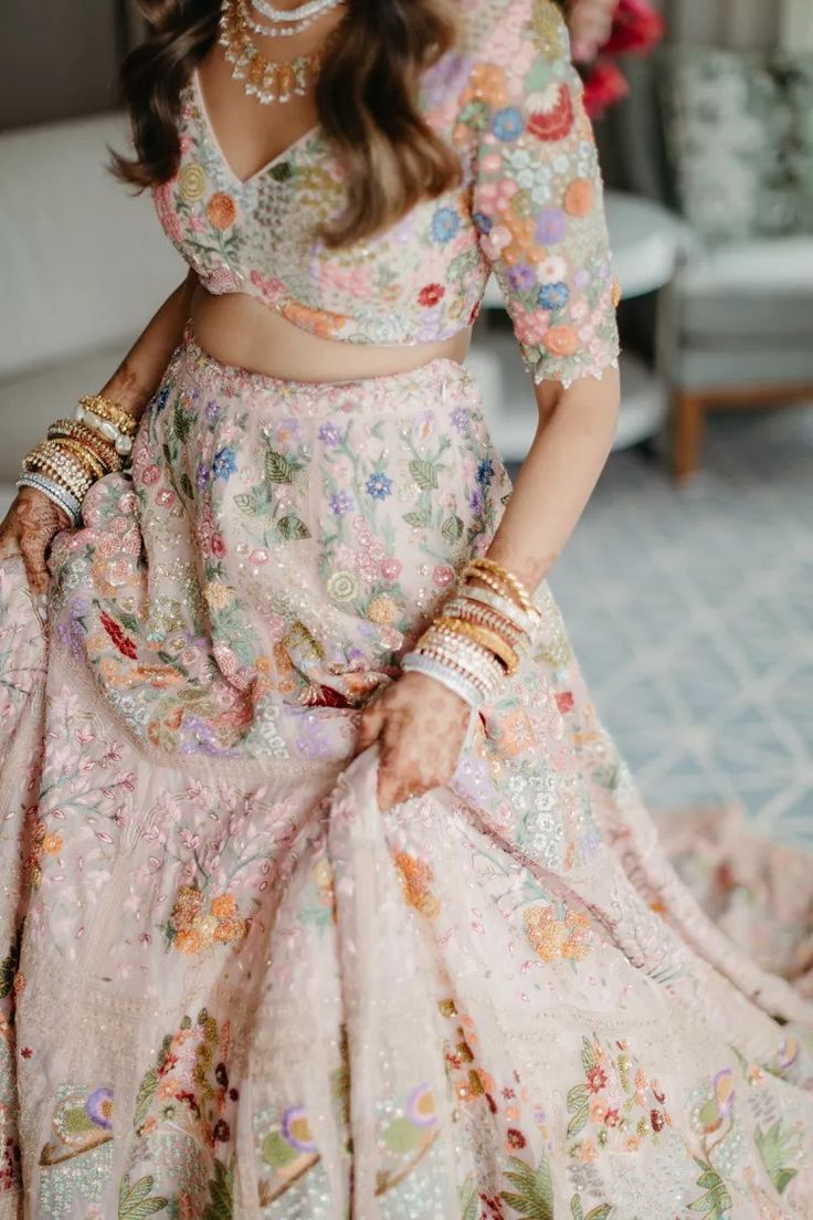 a woman in a pink and green floral print lehenga is posing for the camera