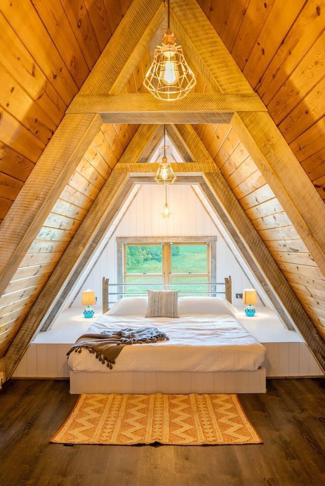 an attic bedroom with wooden walls and flooring is decorated in white, wood - paneled ceilings