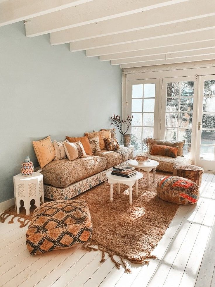 a living room filled with furniture and lots of pillows on top of a wooden floor