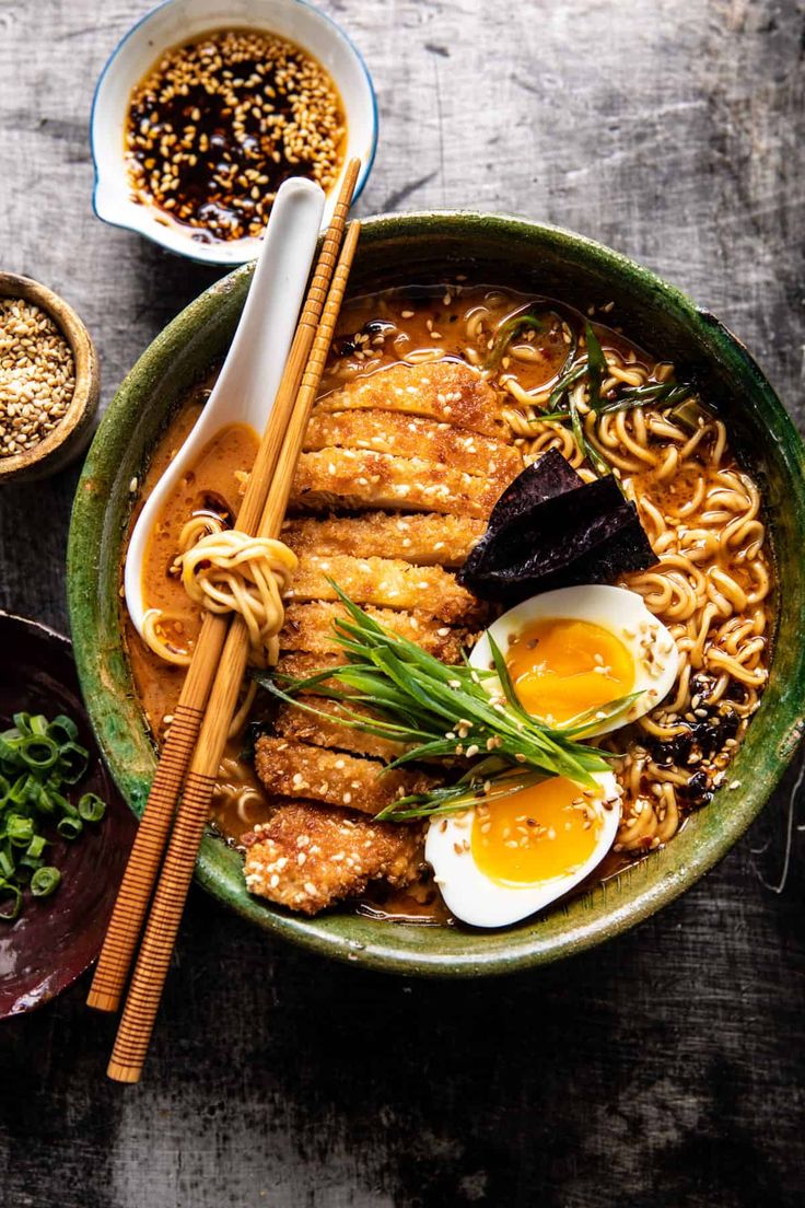 an overhead view of a bowl of ramen with chopsticks and eggs on the side