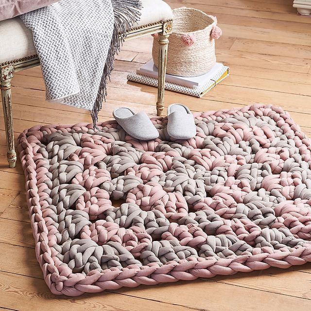 a pair of slippers sitting on top of a pink and gray blanket next to a chair