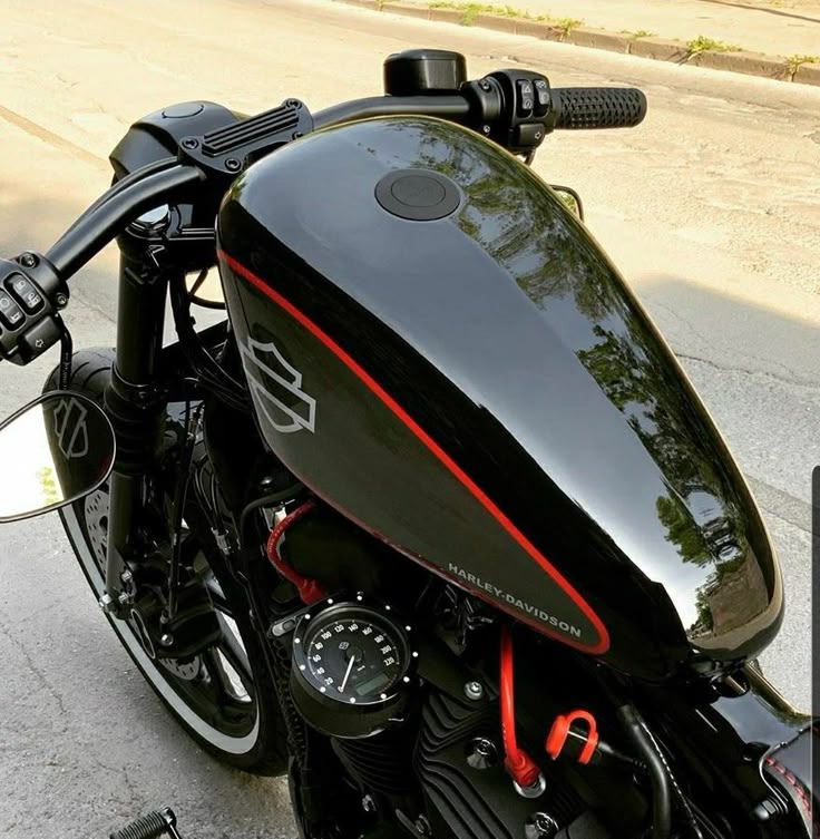 a black motorcycle parked on the street next to a curb with trees in the background