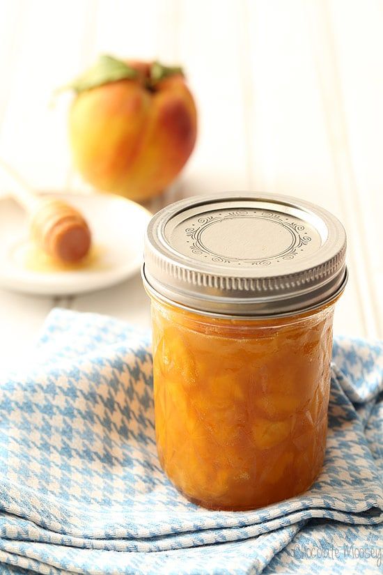 a glass jar filled with orange marmalade sitting on top of a blue and white towel