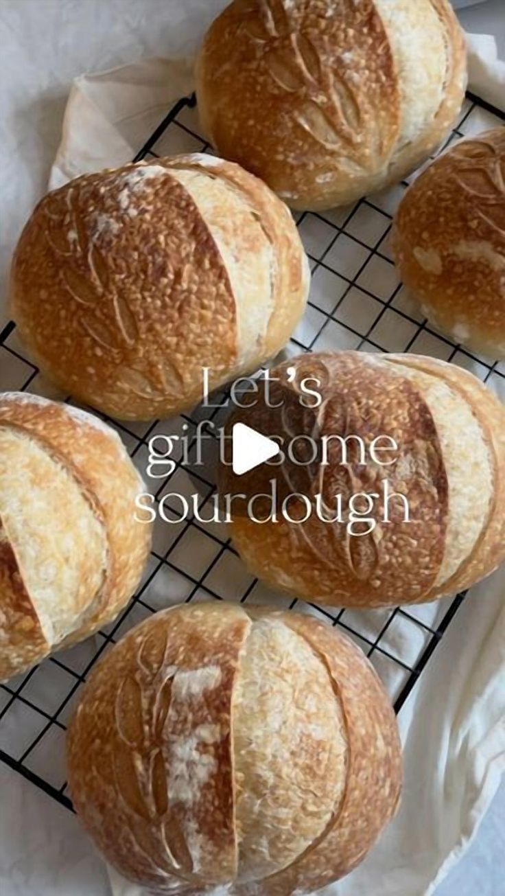 four loaves of bread sitting on top of a cooling rack with the words let's gift some sourdough