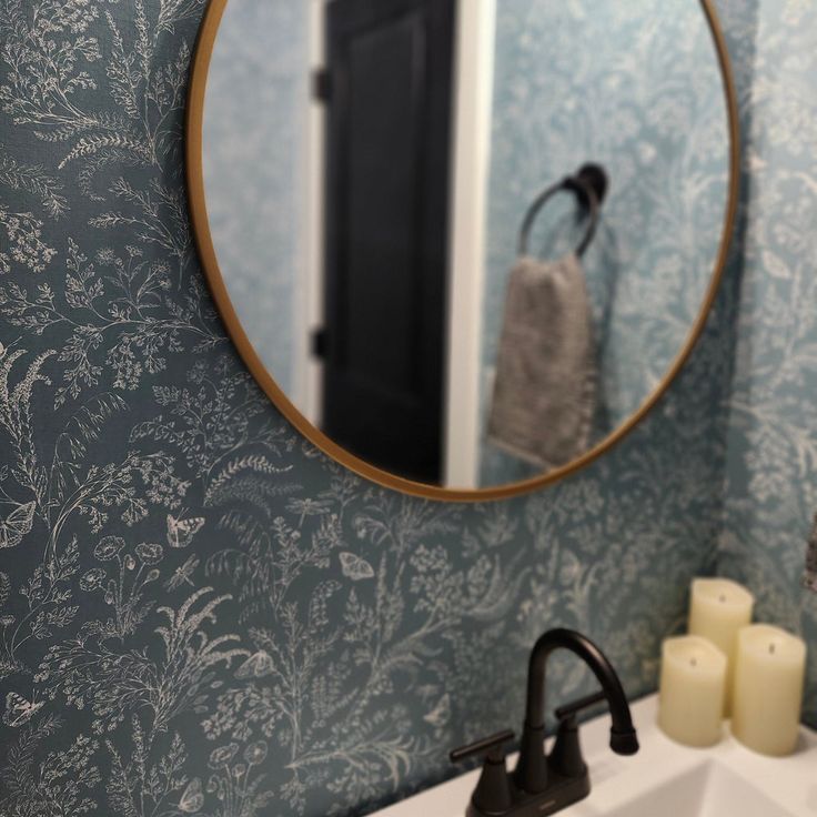 a bathroom sink sitting under a mirror next to a wall mounted faucet with candles on it