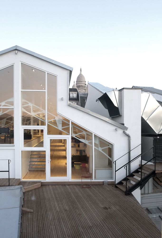 a white building with stairs leading up to it's second floor and the roof