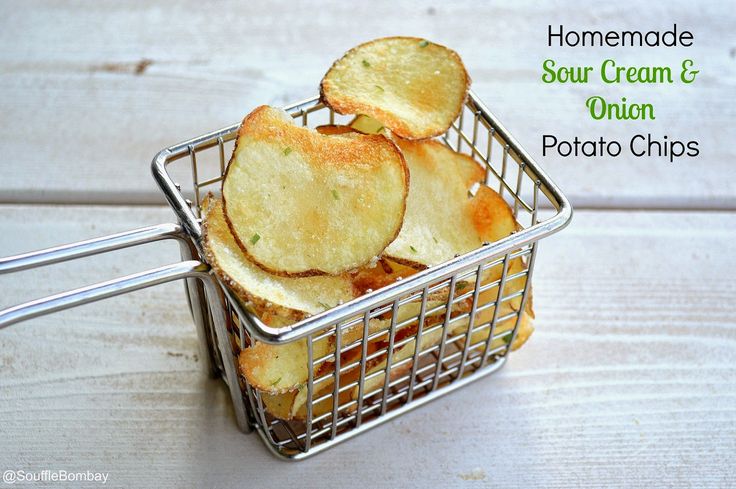 homemade sour cream and onion potato chips in a wire basket on a white wooden table