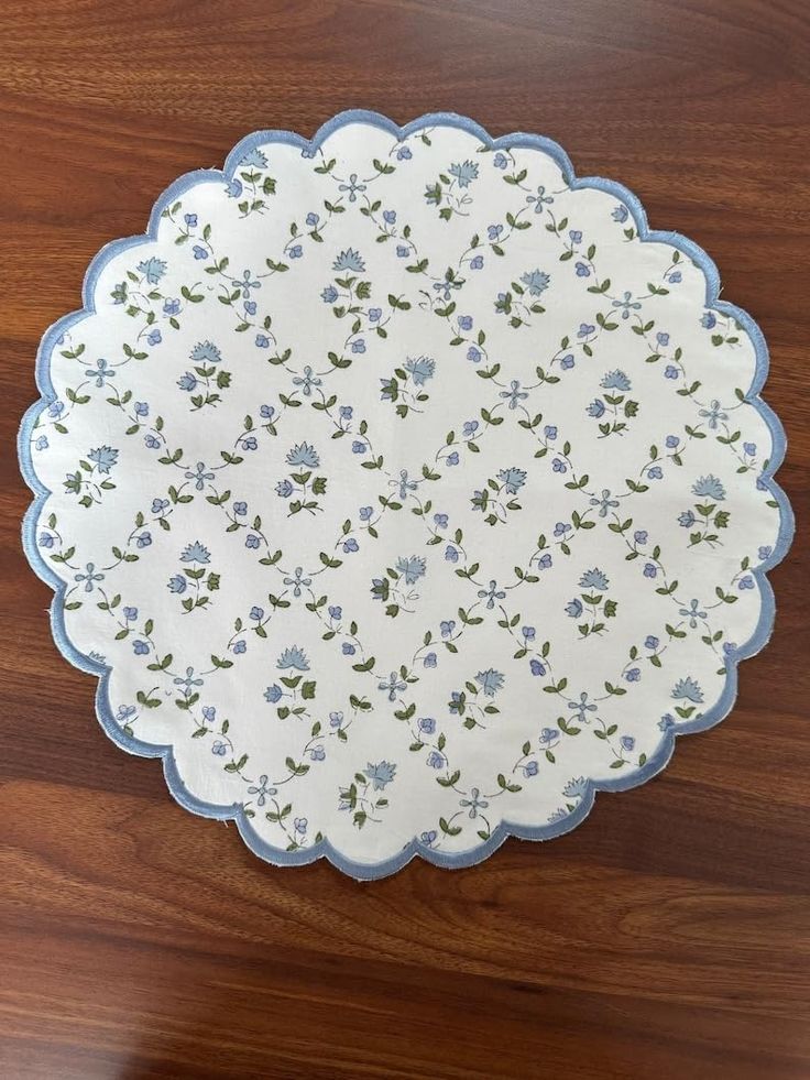 a white and blue plate with flowers on it sitting on a wooden table next to a knife