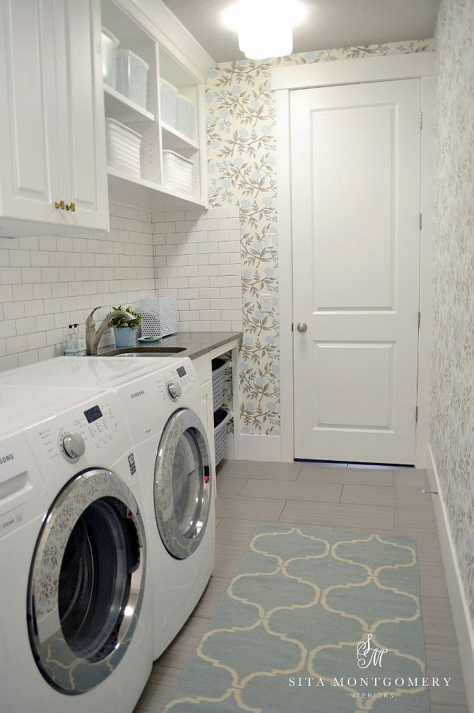 a washer and dryer in a small room next to a door with floral wallpaper