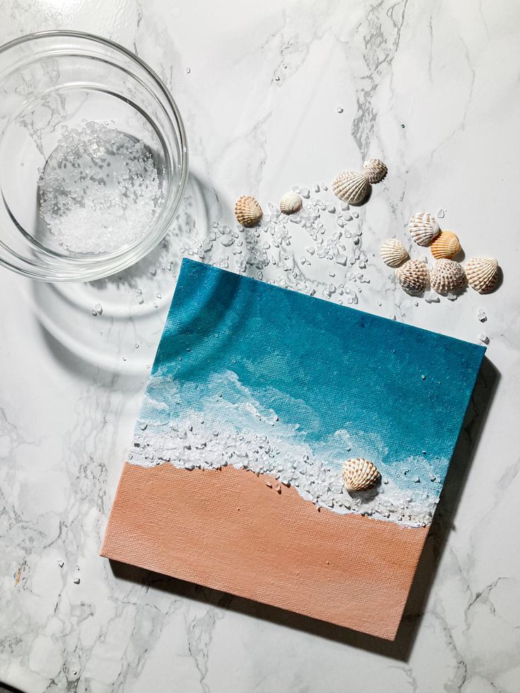 seashells are scattered around a painting on a marble surface