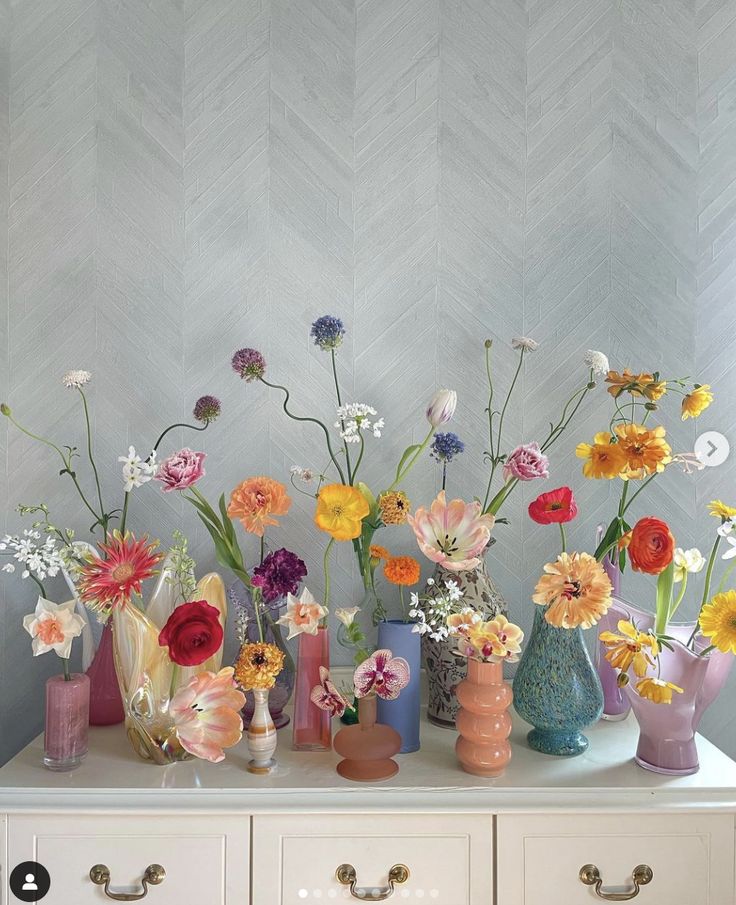 there are many different vases with flowers in them on the table next to each other