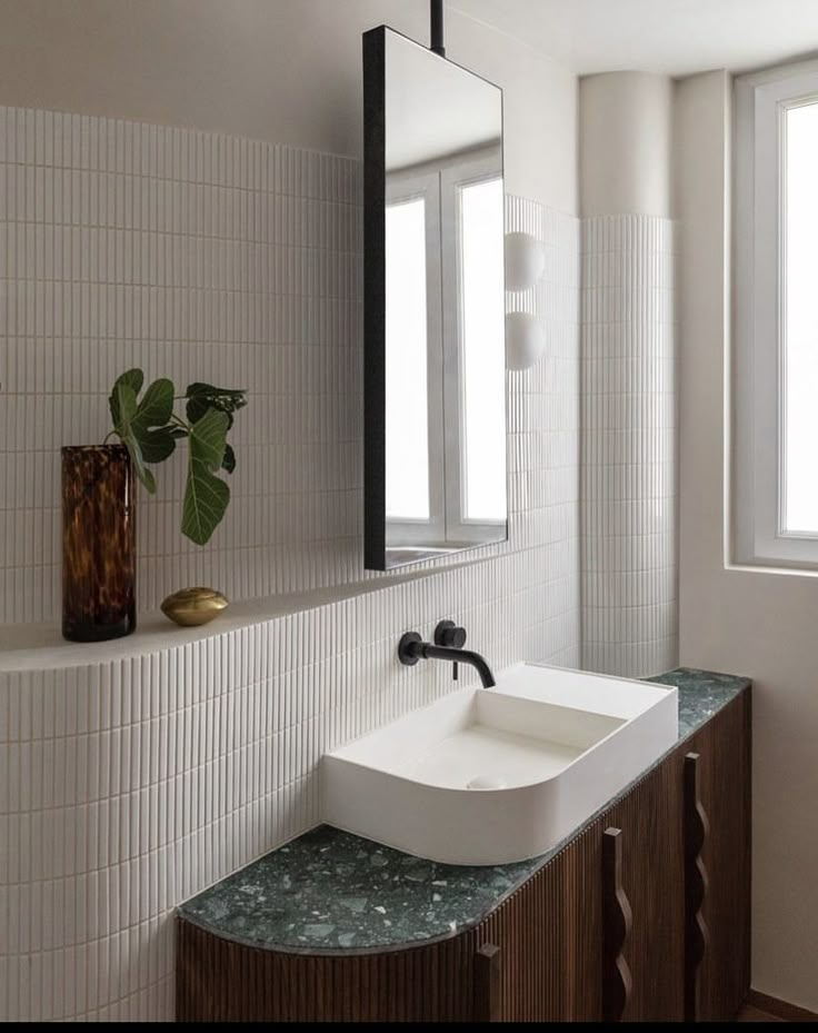 a white sink sitting under a bathroom mirror next to a wooden cabinet and counter top