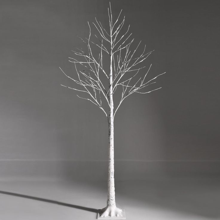 a white tree with no leaves on it in the middle of a gray background,