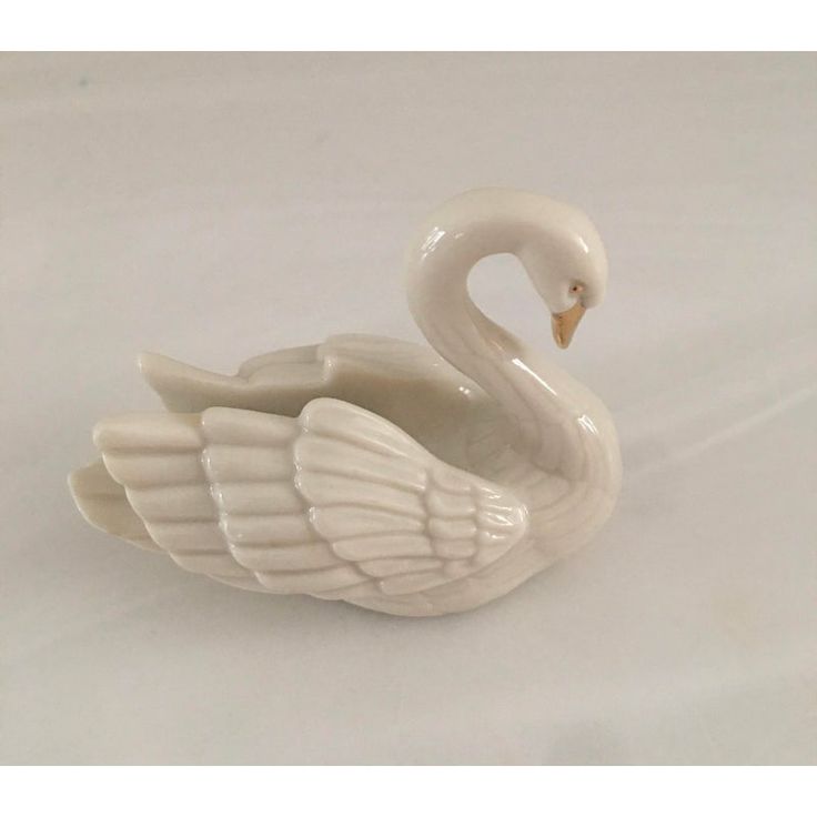 a white ceramic swan figurine on a white background