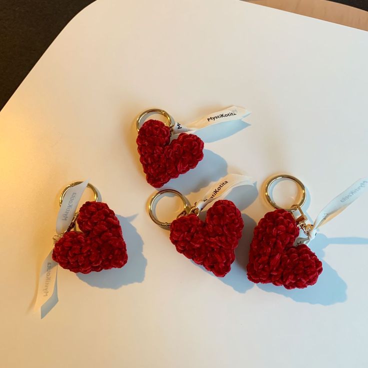 three red crocheted heart shaped keychains sitting on top of a table