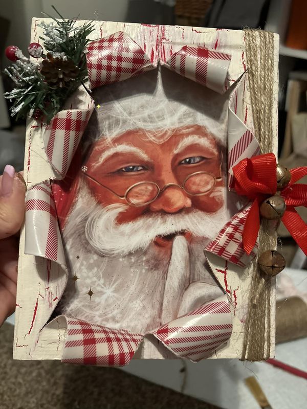 someone holding up a christmas card with a santa clause on it and a red bow