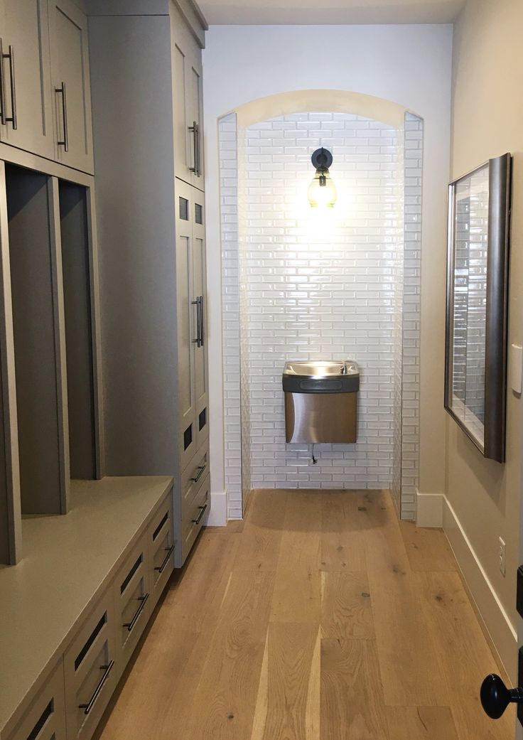 an empty bathroom with white cabinets and wood flooring