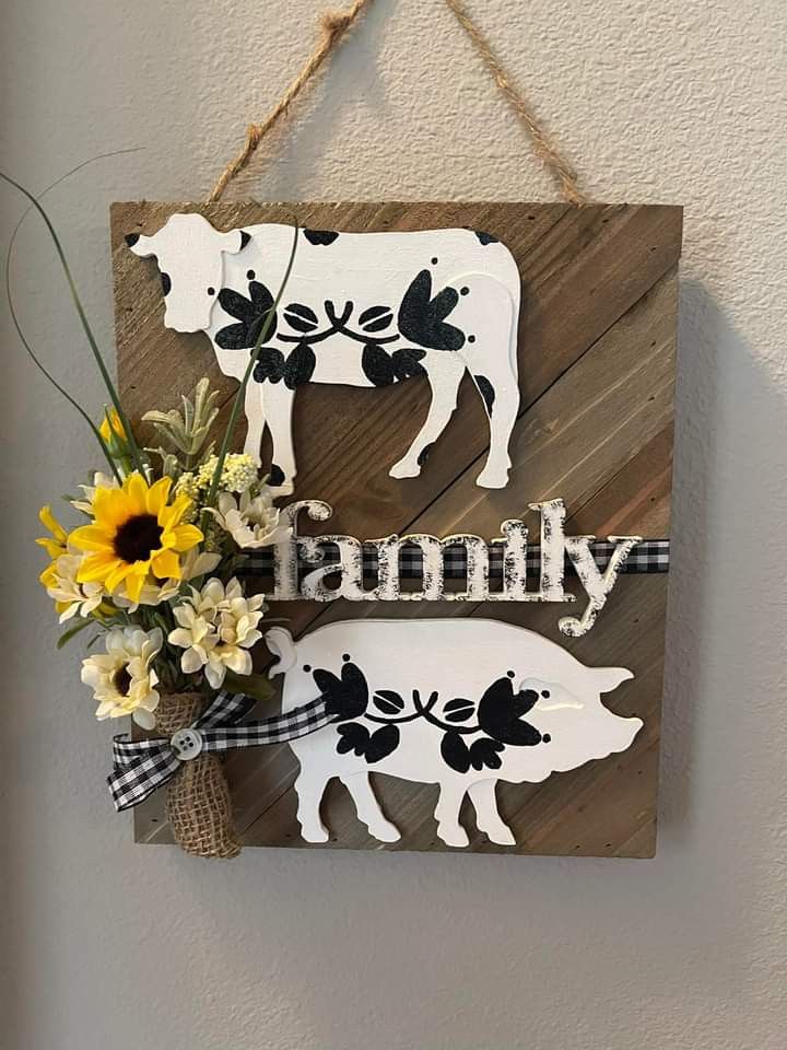 a wooden sign that says family with a cow and flowers hanging from the side of it