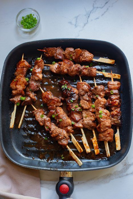 skewered meat and vegetables in a pan on a table