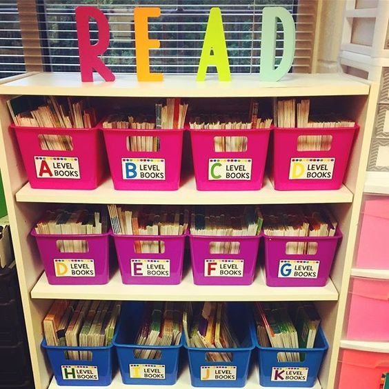 a book shelf filled with lots of books and plastic bins next to a window