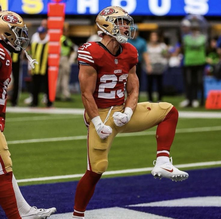 two football players standing on the sidelines with their feet in the air and people watching