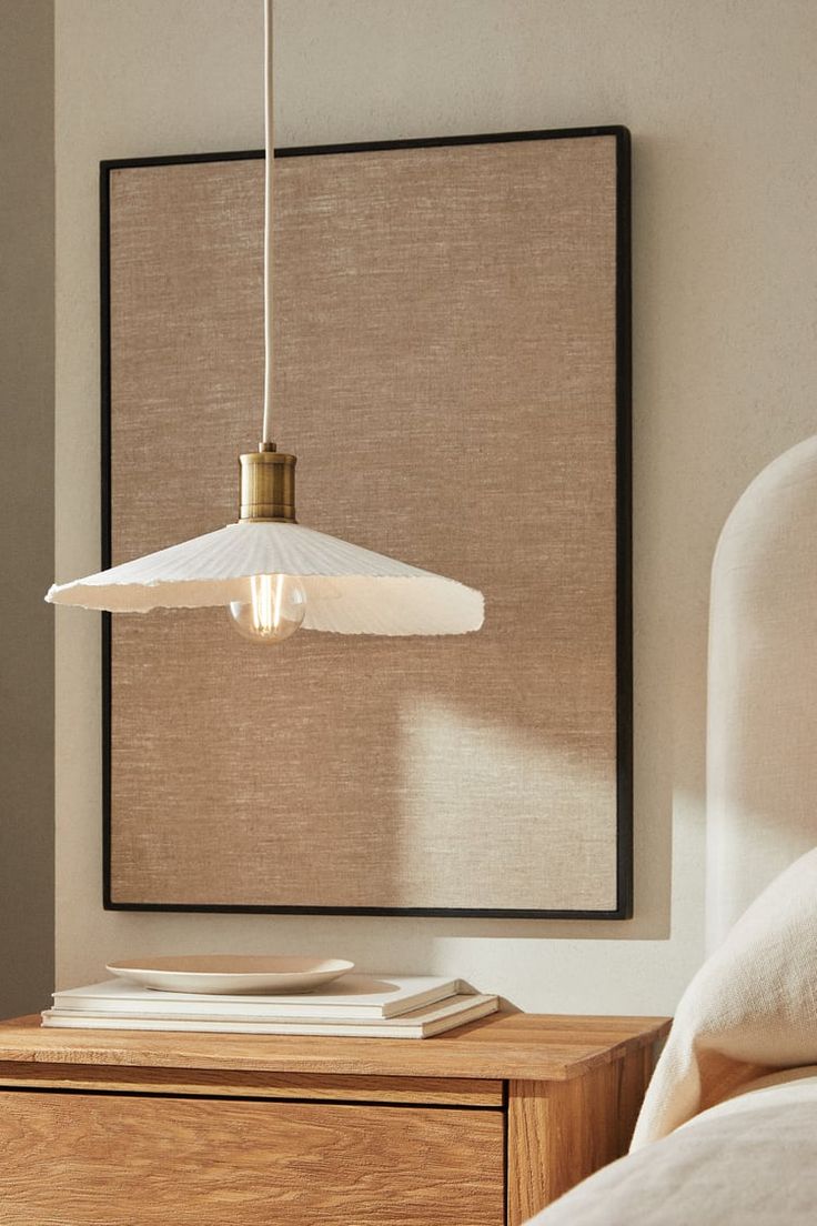 a white lamp hanging over a bed in a bedroom