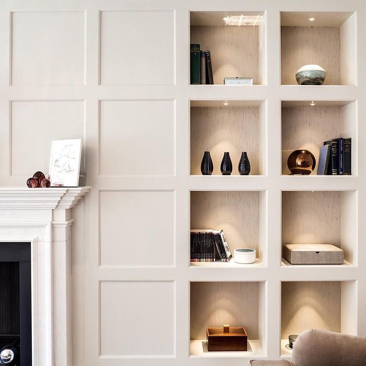 a white book shelf filled with books next to a fireplace