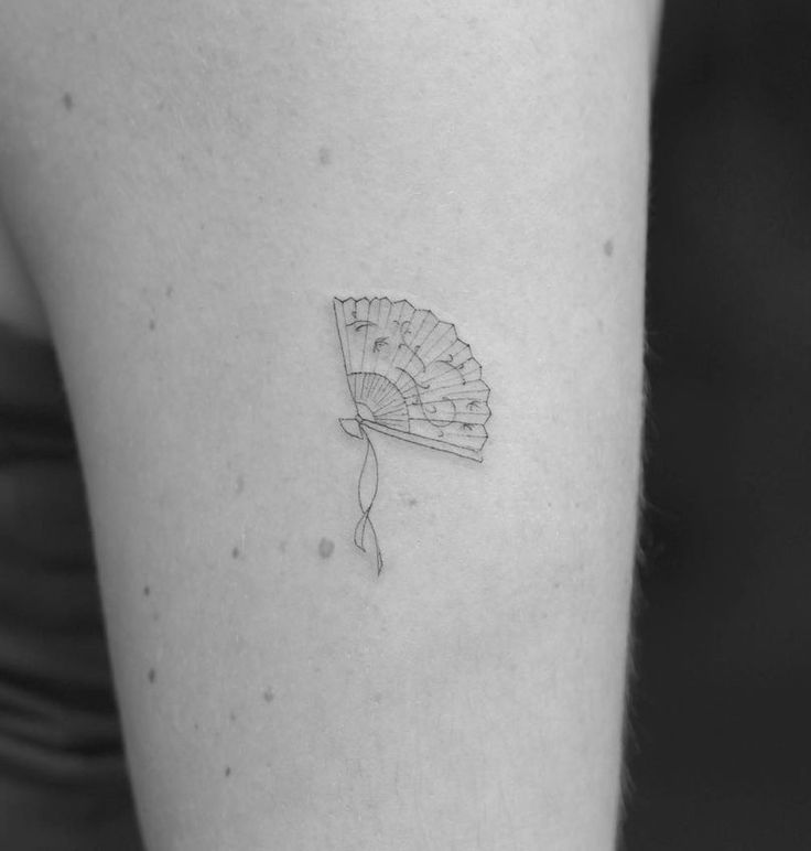 a small fan tattoo on the back of a woman's left arm and leg