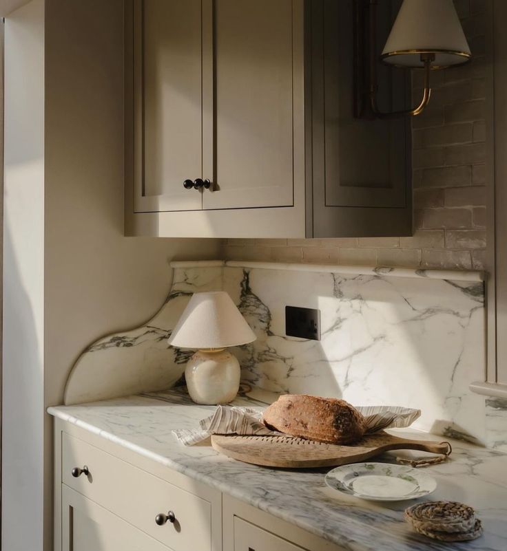 a marble counter top in a kitchen with wooden cabinets and an old fashioned lamp on it