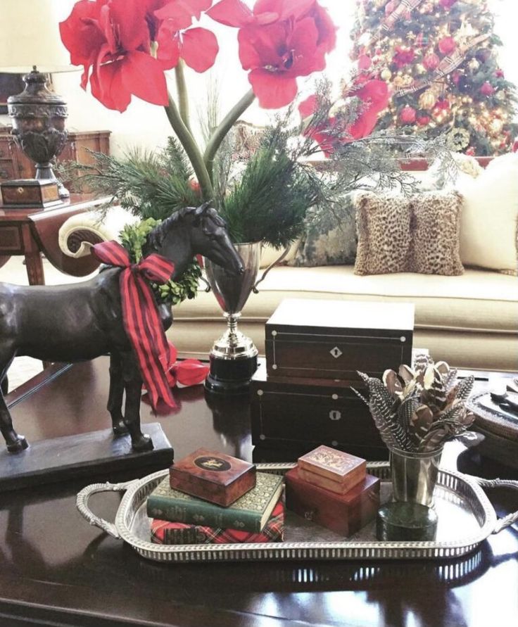 a horse figurine sitting on top of a table next to a christmas tree