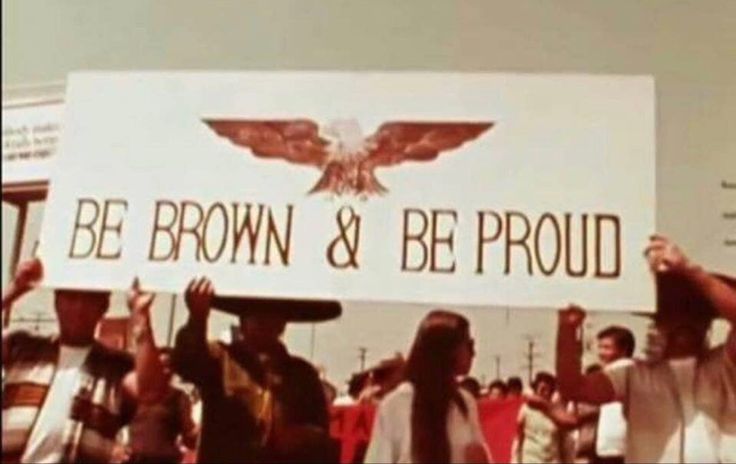 a group of people holding up a sign that says be brown & be proud