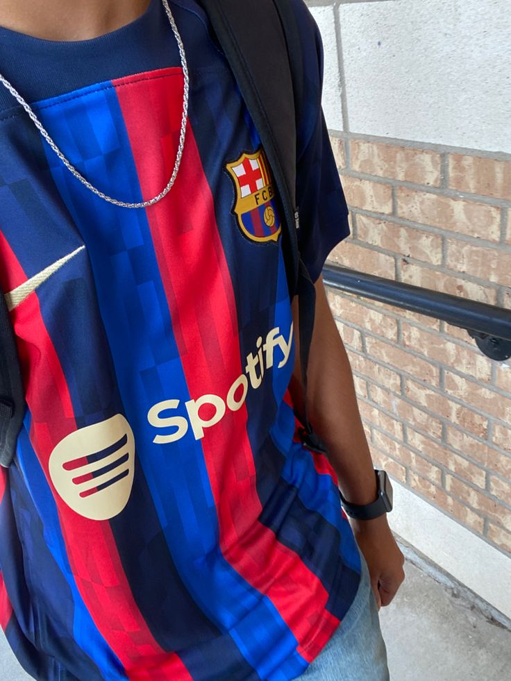 a man wearing a blue and red striped shirt with a black backpack on his back