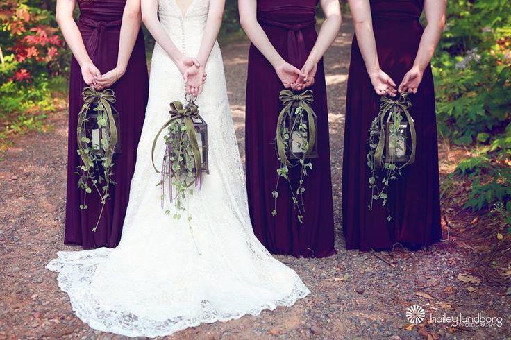 four bridesmaids in maroon dresses holding bouquets with greenery on the back